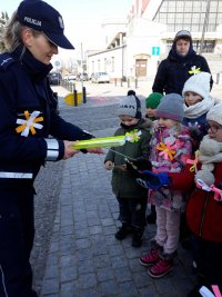 Policjantka rozdająca odblaski dzieciom z akademi