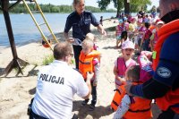 Policjant omawiający prawidłowe założenie kamizelki ratunkowej