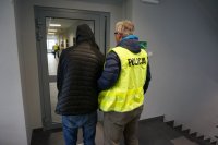 Policjanci doprowadzają zatrzymanego do komendy policji