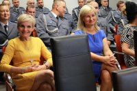 pracownicy cywilni uśmiechnięci na tle policjantów  ubranych w mundury galowe