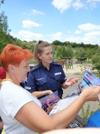 policjantka pokazuje plakat akcji bezpieczeństwo nad wodą