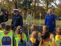 policjant  w mundurze  oprowadza dzieci po miasteczku rowerowym