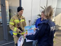 policjantka i strażak przyklejają plakat akcji