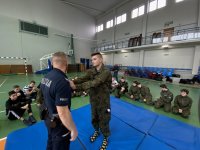 uczniowie klasy mundurowej na hali sportowej ćwiczą z policjantami