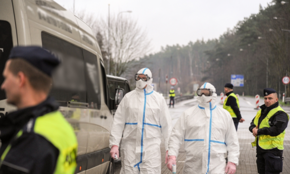 policjanci i osoby ubrane w specjalne kombinezony dokonują kontroli drogowej