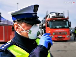 policjant ruchu drogowego w maseczce ochronnej obserwuje ruch drogowy