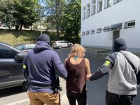 policjanci po cywilnemu w kominiarkach  prowadzą zatrzymaną