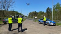 Policjanci stojący przy drodze a nad nimi dron