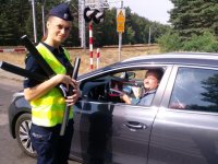 Policjantka rozdaje ulotki kierowcy samochodu