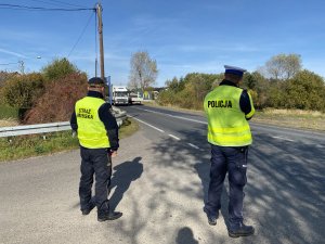 Policjant i Strażnik Miejski w mundurach mierzą prędkość pojazdów