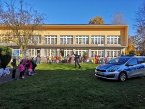 policjantka, dzieci i radiowóz na tle przedszkola