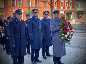 Policjanci i strażak stoją z wieńcem