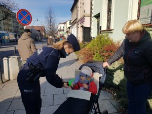 Policjantka zakłada dziecku na rączkę odblask