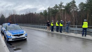 Umundurowani policjanci na mocie dokonują pomiaru odległości