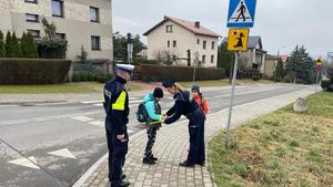 Policjanci wręczają odblaski dzieciom