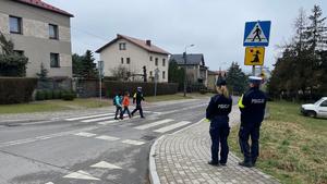 Policjant przeprowadza pieszych przez przejście dla pieszych