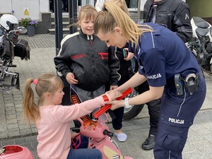 Policjantka zakłada dziecku odblask na rękę