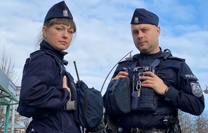 Policjant i policjantka stoją przy radiowozie