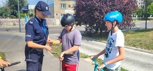 Policjantka zakłada odblask na rękę dziecku