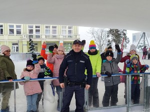 na zdjęciu grupa osób stojąca na lodowisku oraz umundurowany policjant