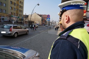 na zdjęciu widoczny umundurowany policjant, który obserwuje przejście dla pieszych