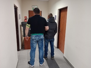 na zdjęciu nieumundurowany policjant, który trzyma zatrzymanego