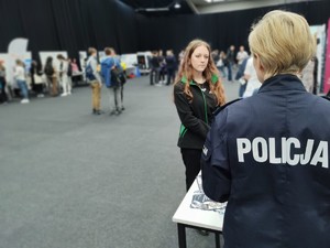 na zdjęciu policjantka w umundurowaniu, która rozmawia z dziewczyną przy stoisku informacyjnym