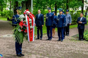 na zdjęciu grupa umundurowanych policjantów wraz z zastępcą prezydenta miasta. Jeden z policjantów trzyma wieniec z kwiatami.