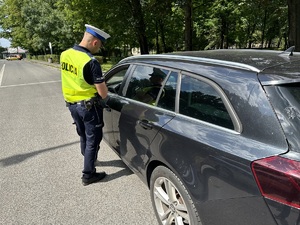 na zdjęciu umundurowany policjant, który stoi przy pojeździe