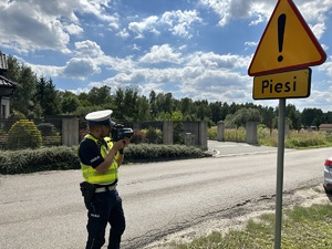 na zdjęciu umundurowany policjant, który dokonuje pomiaru prędkości na poboczu