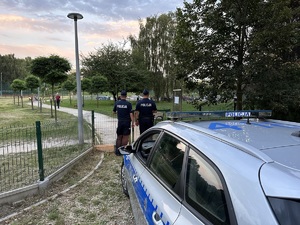 na zdjęciu dwóch umundurowanych policjantów, którzy obserwują plac zabaw