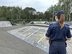 na zdjęciu umundurowana policjantka obserwująca jeżdżące na rowerach dzieci na pumptrucku