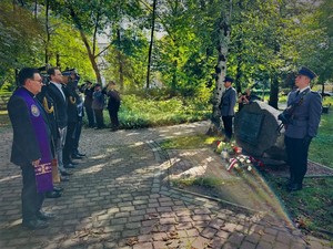 na zdjęciu uczestnicy uroczystości stojący przed pomnikiem i oddający honor.