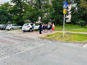 umundurowana policjantka z grupą dzieci przy przejściu dla pieszych