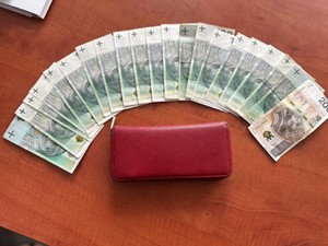 na zdjęciu portfel koloru brązowego, a przy nim rozłożone banknoty