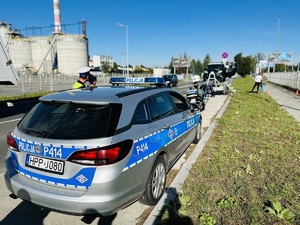 na zdjęciu policjant ruchu drogowego dokonuje pomiaru prędkości przy radiowozie