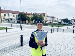 na zdjęciu umundurowana policjantka trzyma opaski odblaskowe ułożone w wachlarzu