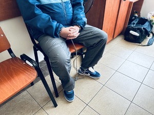 na zdjęciu zatrzymany mężczyzna siedzący na krześle w kajdankach zespolonych