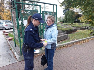 na zdjęciu umundurowana policjantka wręcza opaskę odblaskową kobicie