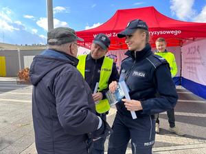 na zdjęciu dwóch umundurowanych policjantów wręcza ulotkę mężczyźnie