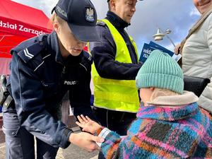 na zdjęciu policjantka wręcza dziecku opaskę odblaskową