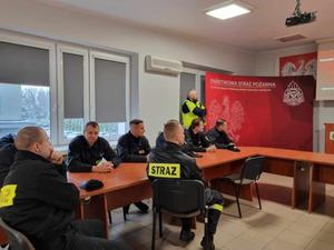 na zdjęciu policjant umundurowany, który przeprowadza szkolenie dla strażaków