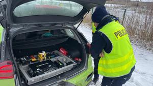 na zdjęciu umundurowany policjant, który obserwuje wnętrze pojazdu autonomicznego