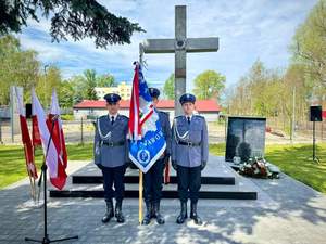 na zdjęciu trzech umundurowanych policjantów, jeden z nich trzyma poczet sztandarowy