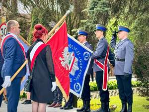 na zdjęciu trzech umundurowanych policjantów, którzy trzymają poczet sztandarowy i oddają honor