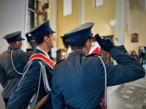 na zdjęciu trzech umundurowanych policjantów trzymających sztandar i oddających honory