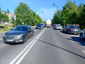 na zdjęciu widoczne pojazdy stojące na drodze, w tym radiowóz policyjny, jeden z pojazdów ma rozbity przód