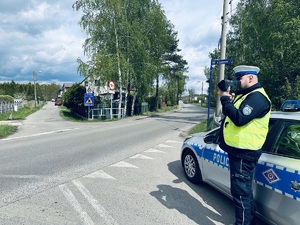 na zdjęciu policjant ruchu drogowego dokonuje pomiaru prędkości na drodze