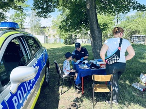 na zdjęciu policjant wykonuje odciski palców chłopczykowi na stoisku profilaktycznym