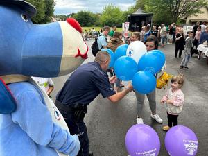 na zdjęciu umundurowany policjant, który rozdaje dzieciom balony